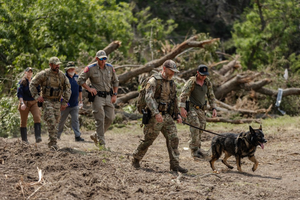 Search and rescue team with cadaver dog searching flood-damaged area.