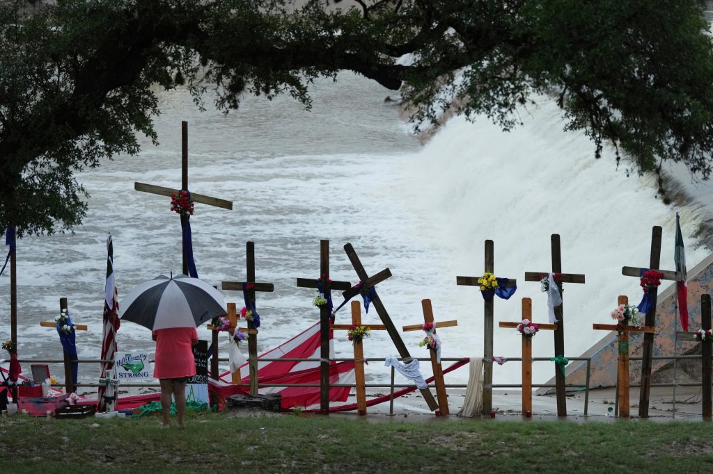 Memorial crosses with flowers at a flooded river.