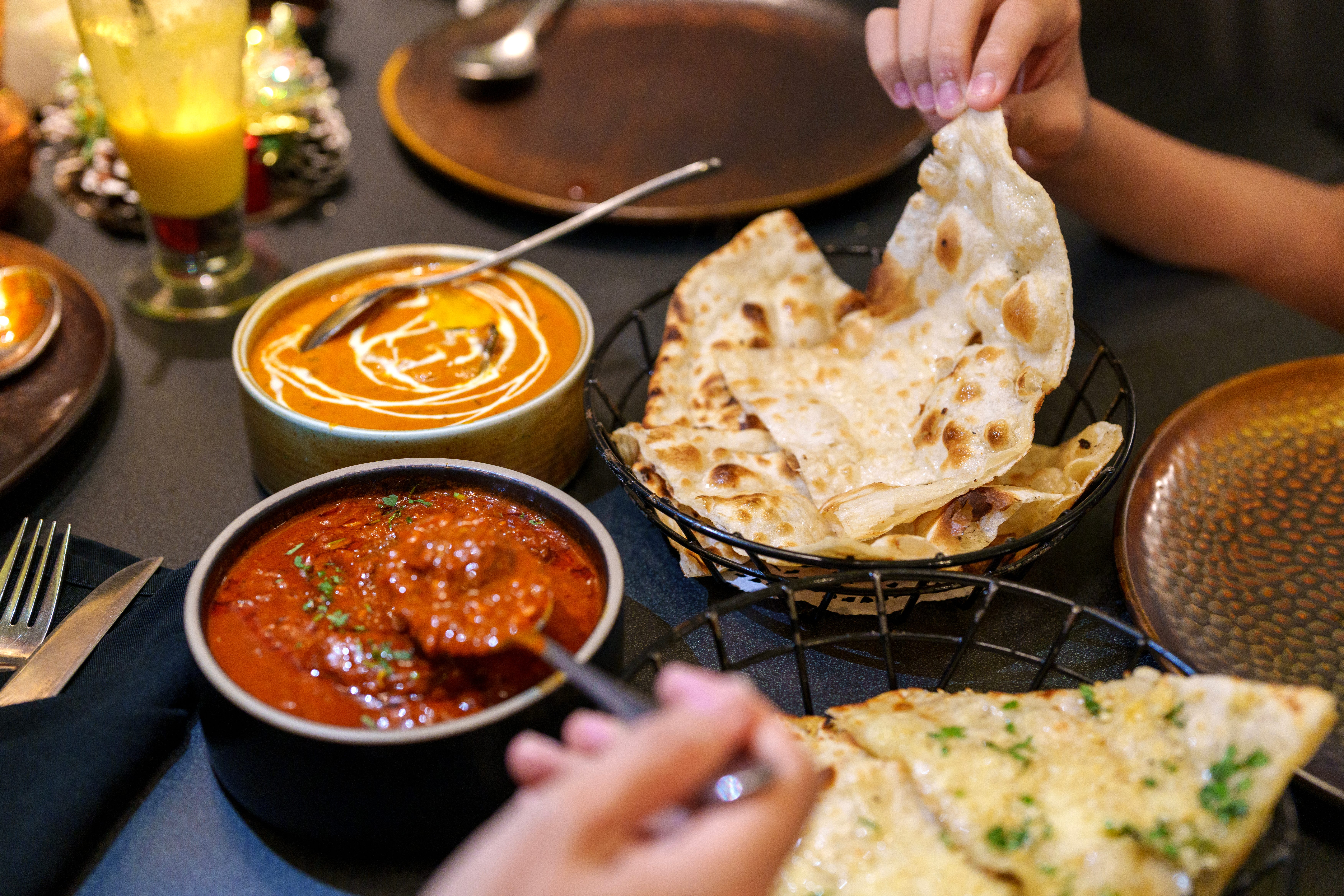 People share Indian food on a black table.