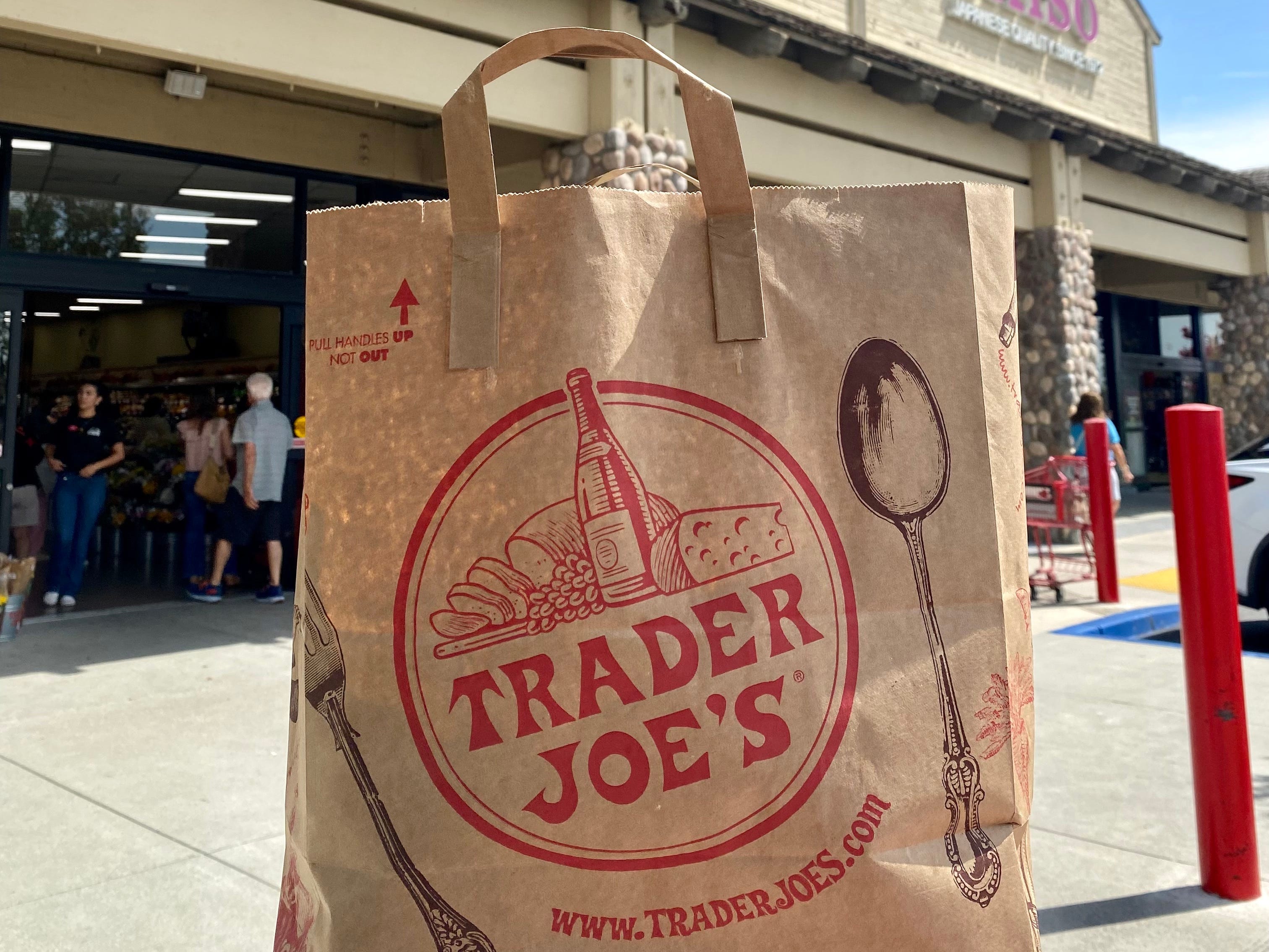 Trader Joe's bag in front of Trader Joe's grocery store sign.