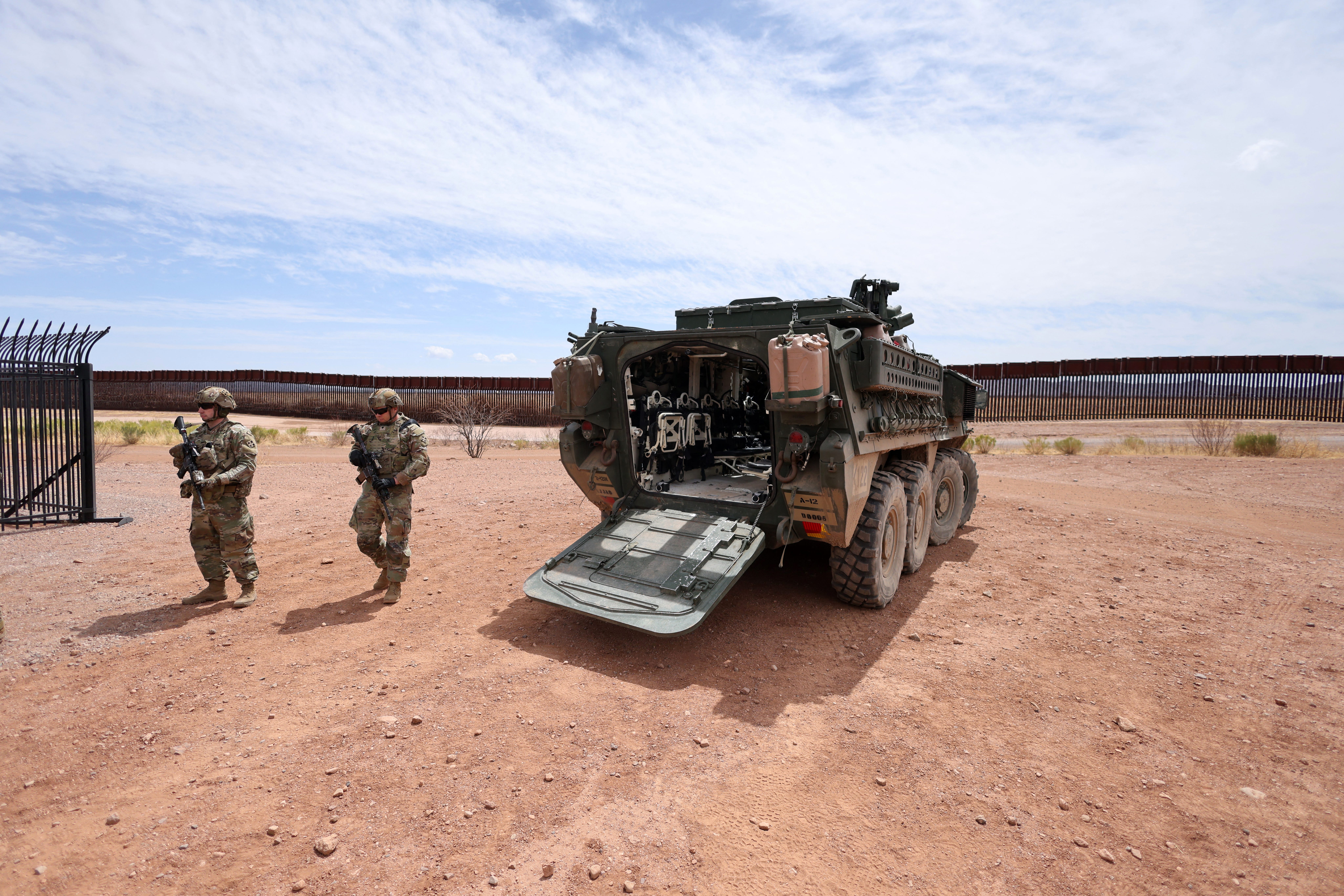 US Army soldiers walk near an Infantry Carrier Vehicle stationed near the southern US border.