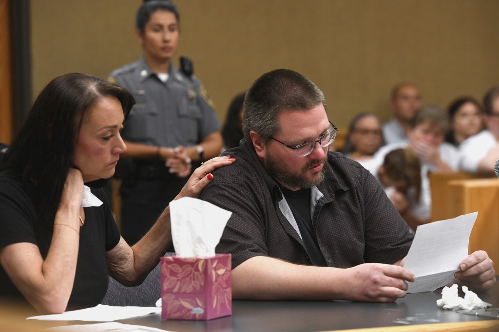 A man reads a victim impact statement while a woman comforts him.