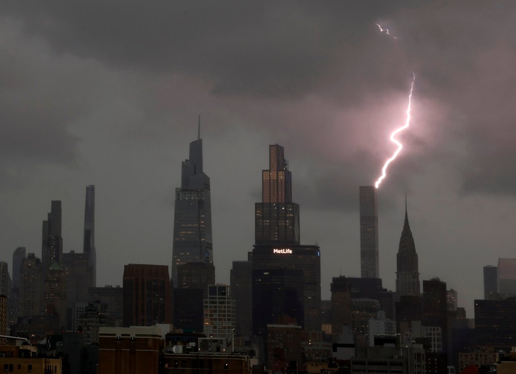 Lightning striking near New York City skyscrapers during a thunderstorm.