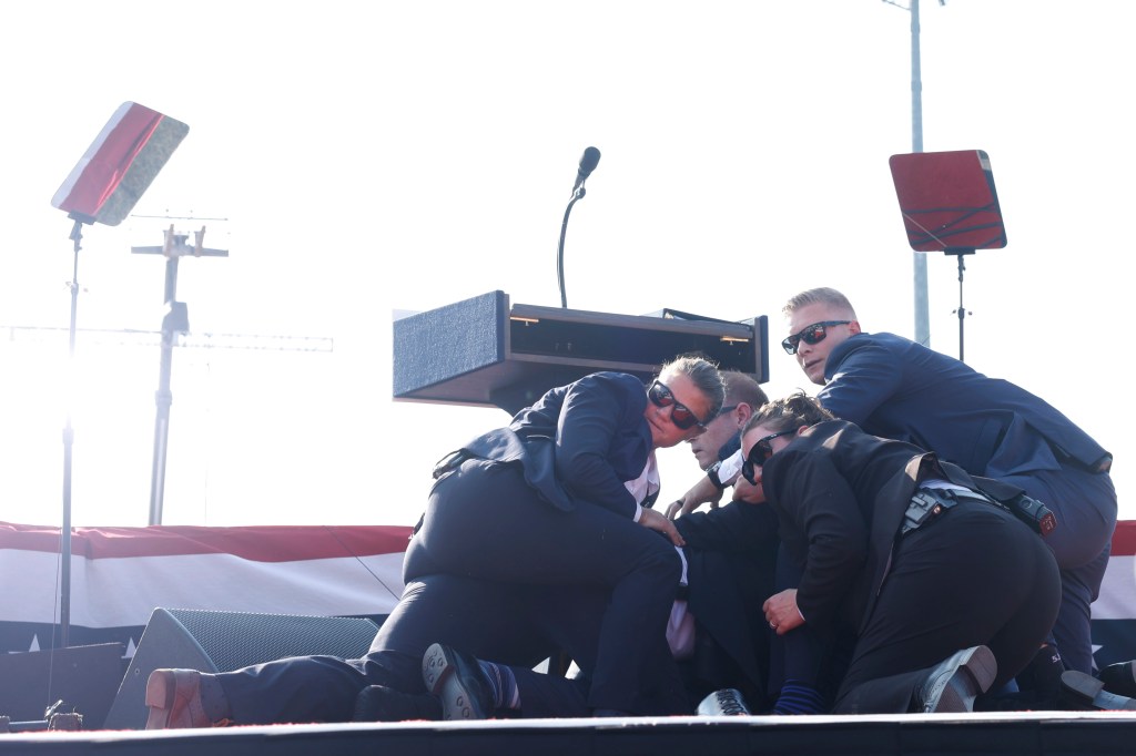 Photo of Donald Trump being helped offstage after a shooting at a campaign rally.