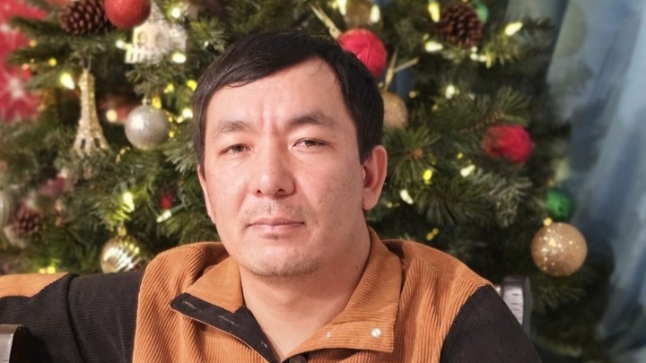 Portrait of Zair Murzakov in front of a Christmas tree.