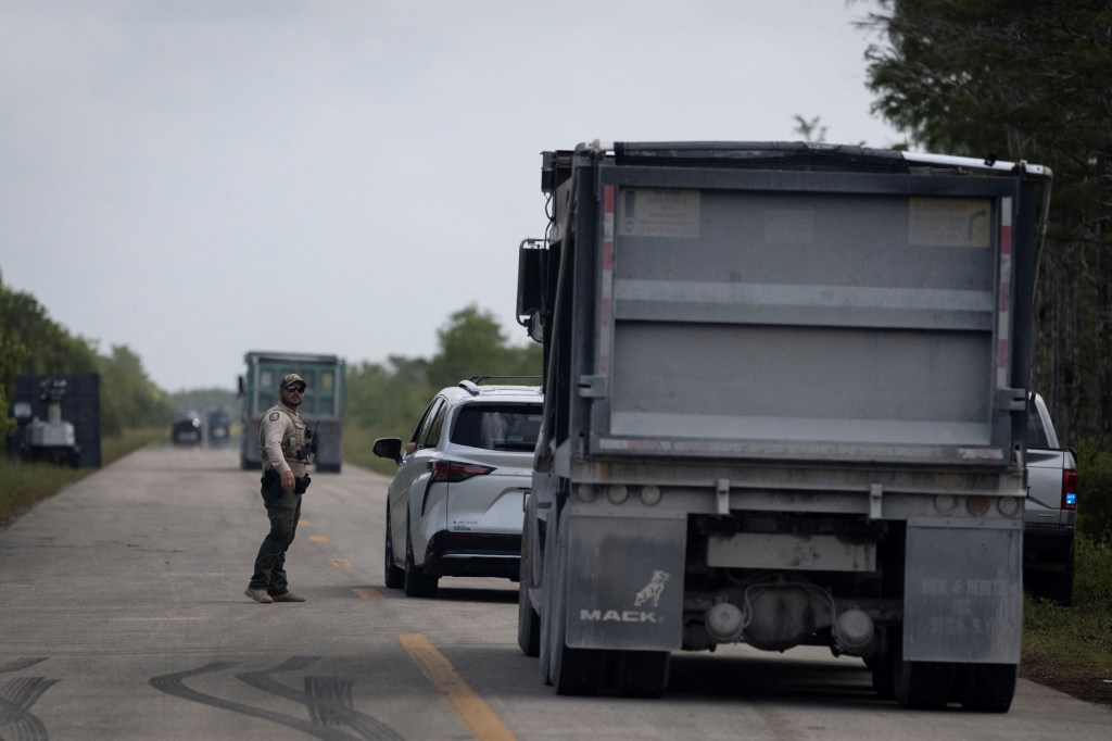 A Collier County Sheriff's deputy directs traffic near a protest against a proposed ICE detention center in Ochopee, Florida.