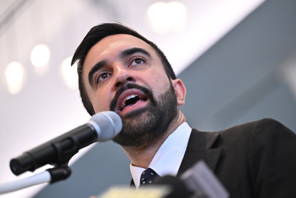 Zohran Mamdani speaking at a microphone.