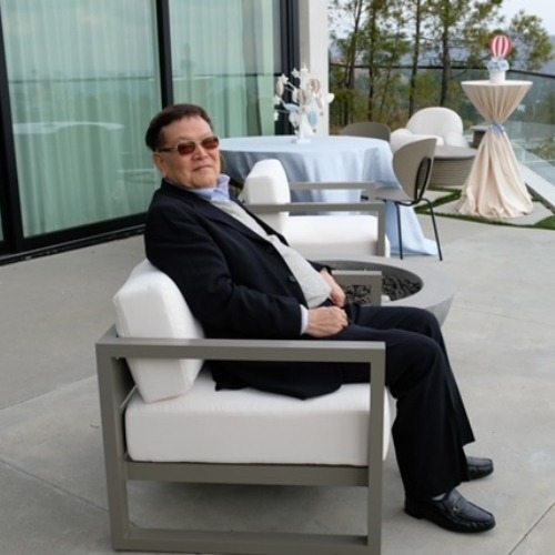 74-year-old Naiping Hou sitting outdoors.