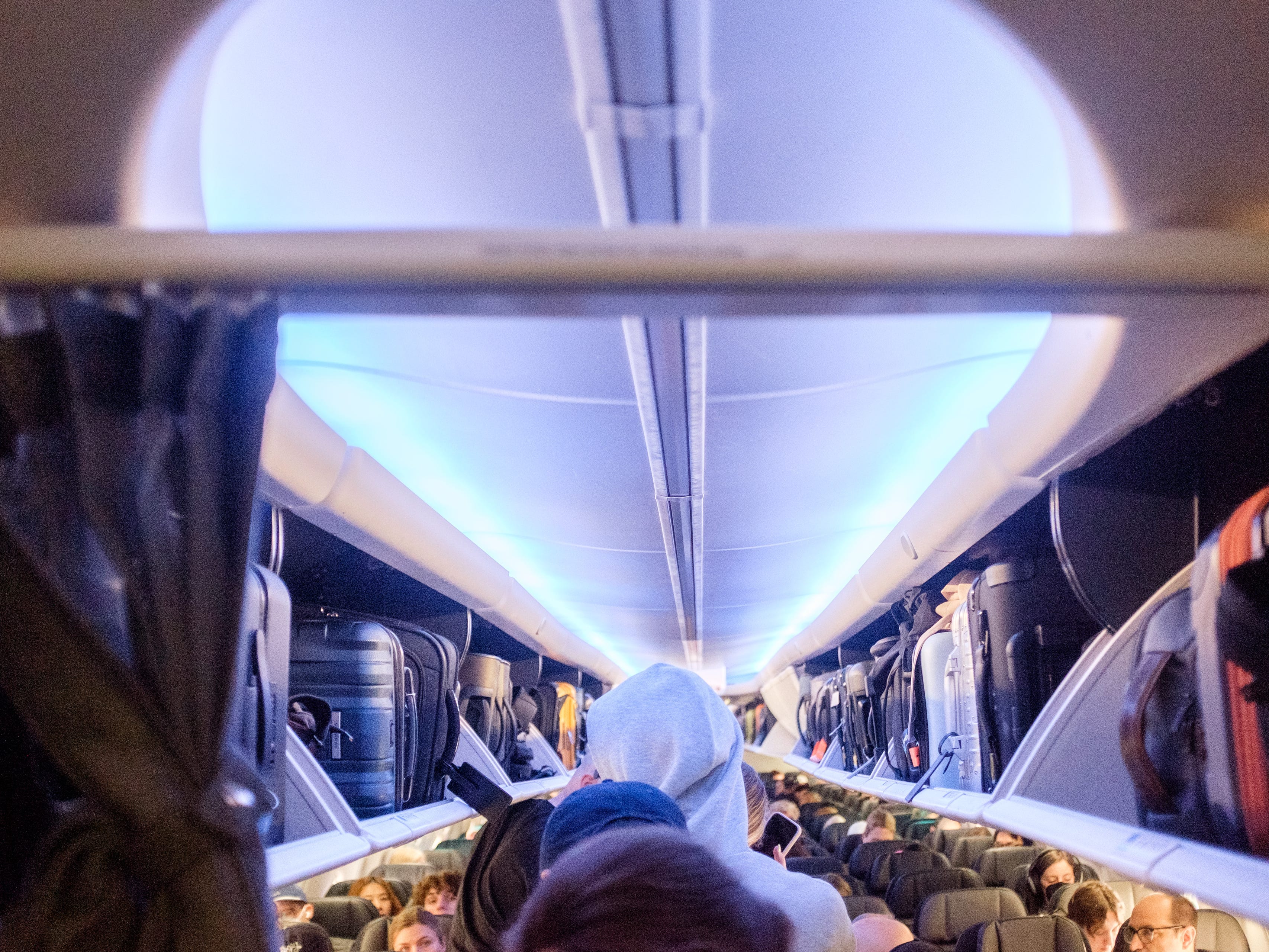 People board a United flight with blue lighting
