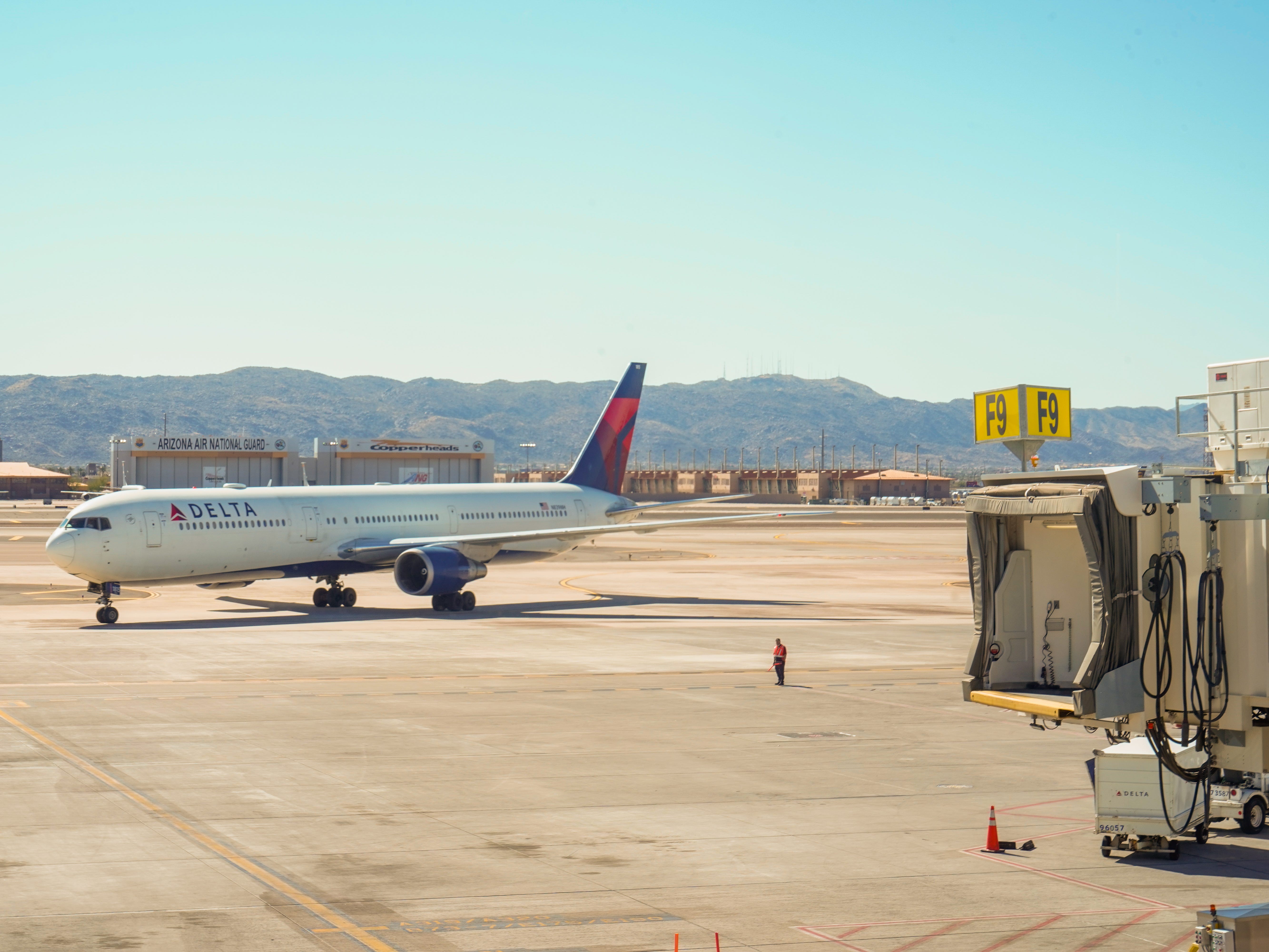 A Delta flight parked on a tarmac with mountains behind