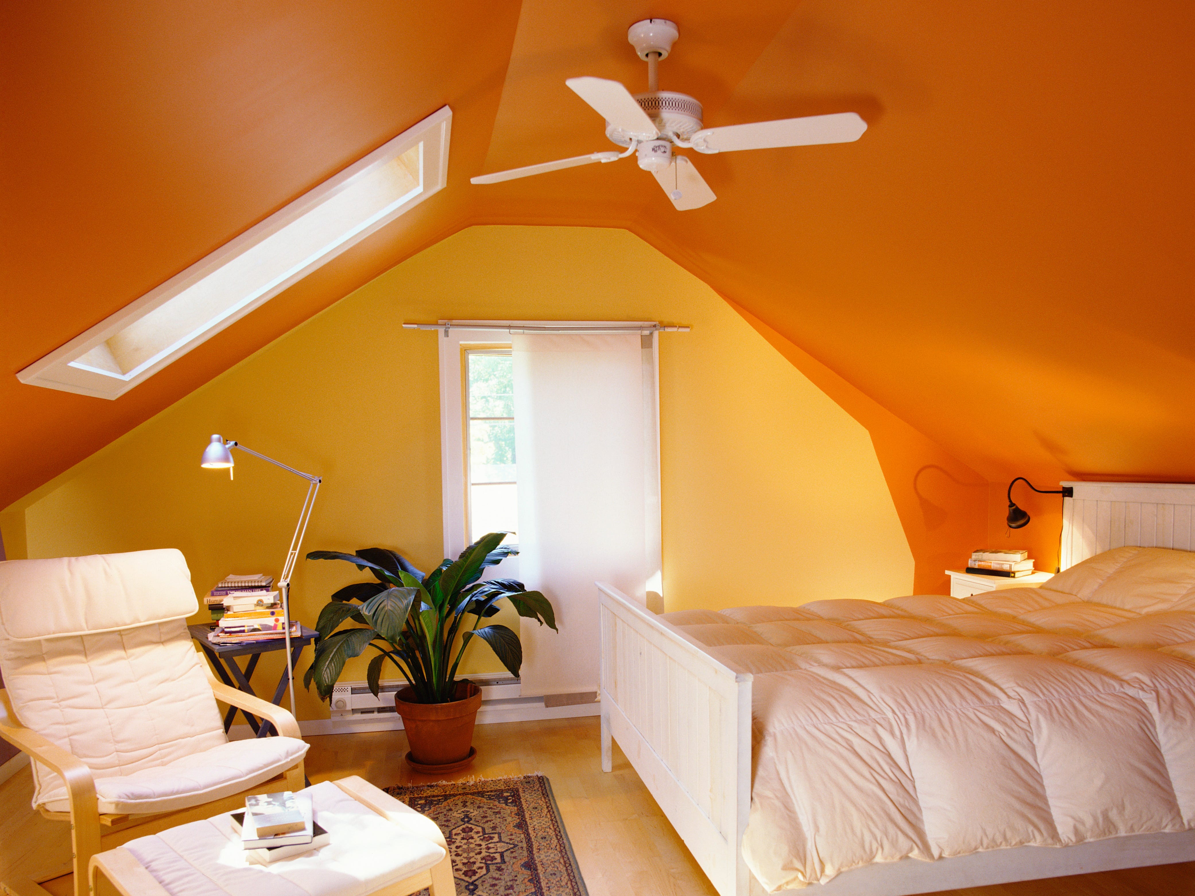 An attic bedroom with yellow walls and a bright orange ceiling.