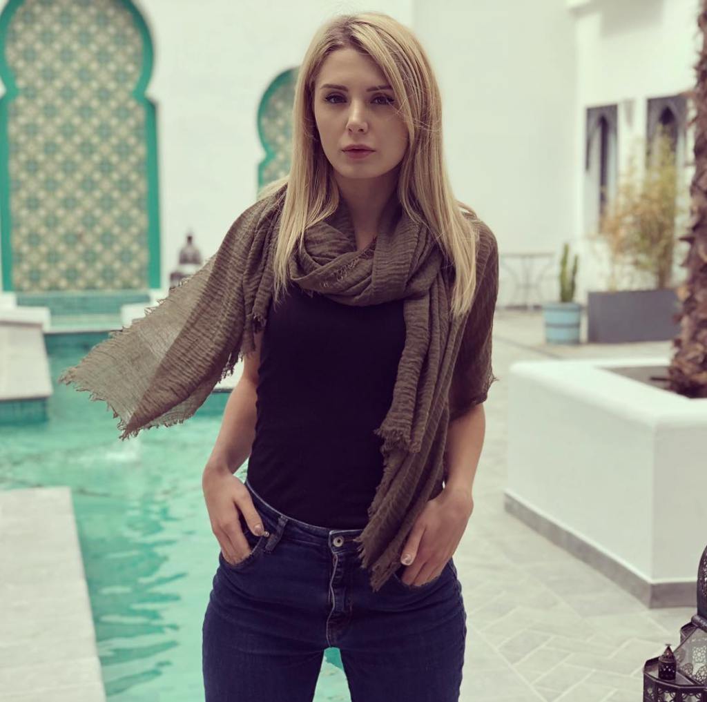 Woman wearing a dark olive scarf and black top, standing outdoors.