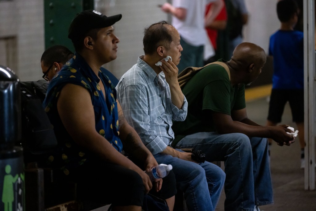 People sitting and wiping sweat during a heatwave.