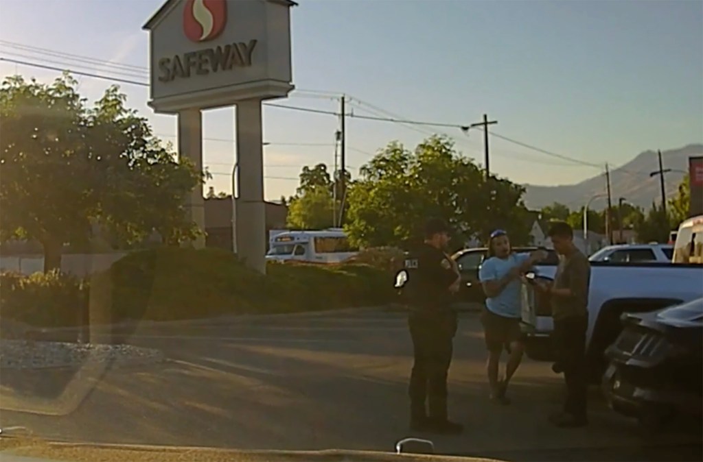 Video still of police officers talking to people in a Safeway parking lot.