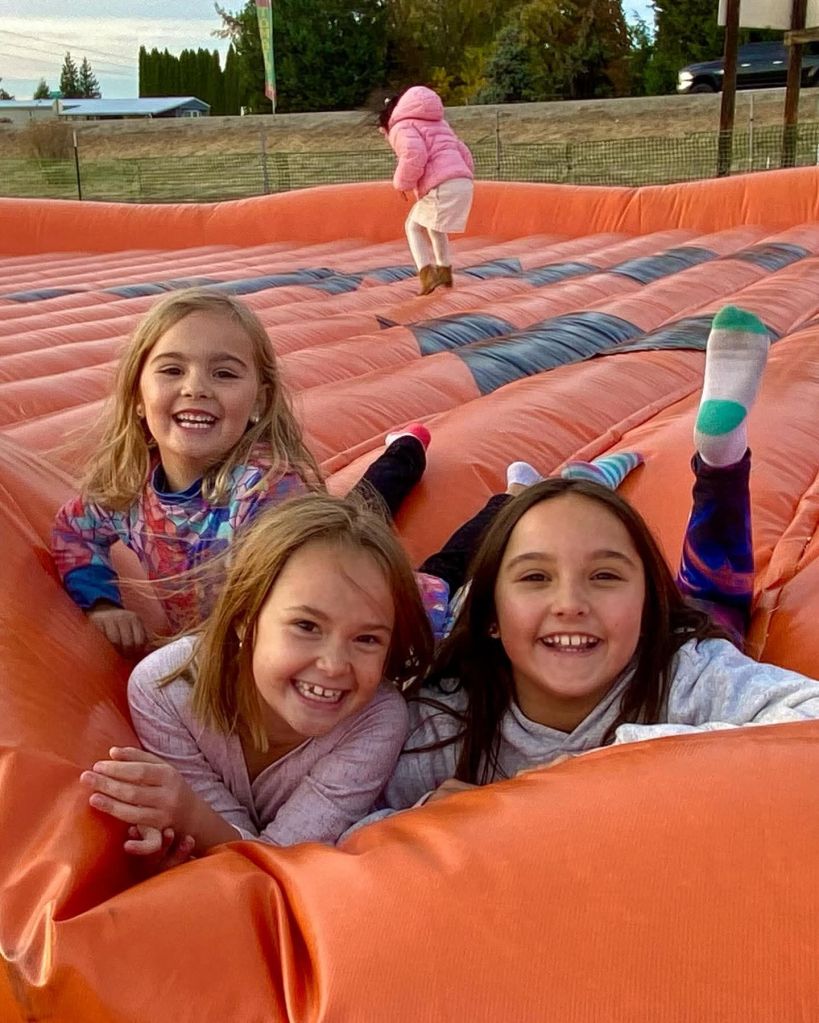 Three young sisters playing on a large inflatable.