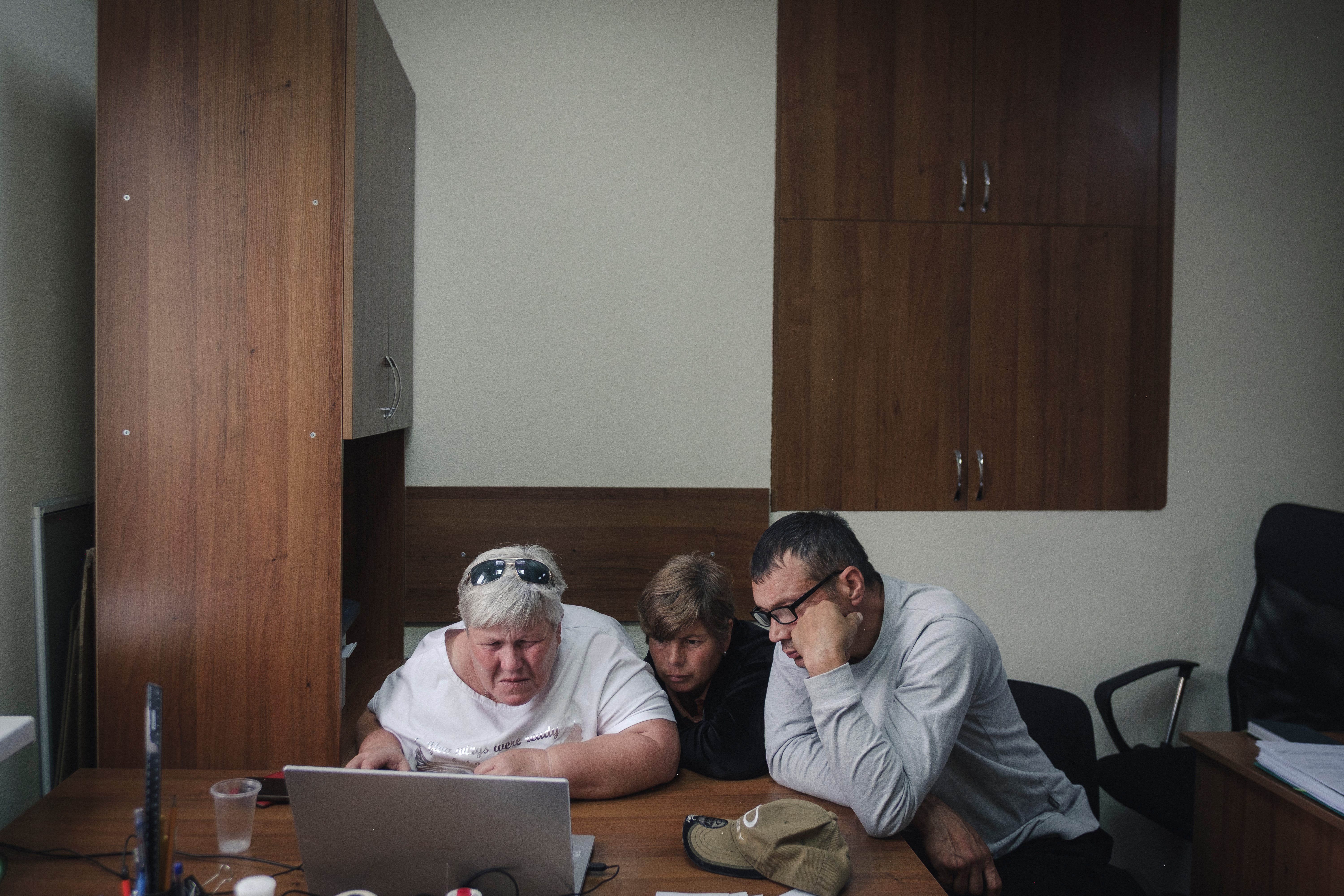 Masha Chuprinchuk (left) and other family members, who declined to give their names, search for her missing son in the digital database of unidentified Ukrainian soldiers at a police station in Kyiv, Ukraine.