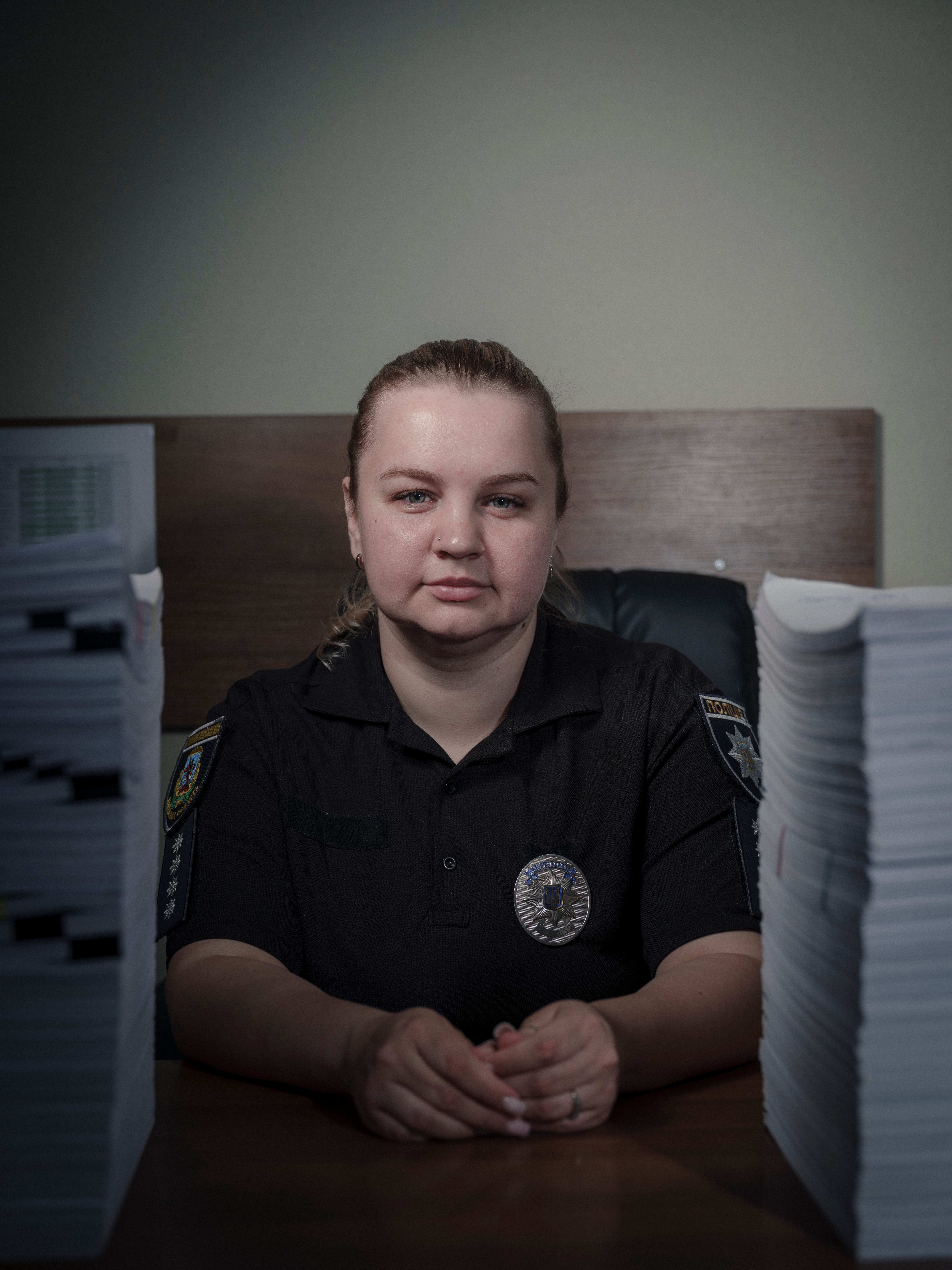 Captain Olha Sydorenko sits for a portrait among stacks of open case files in her office at the Department for Investigating Particularly Serious Crimes at the Investigation Department of the Main Directorate of the National Police in Kyiv Region.