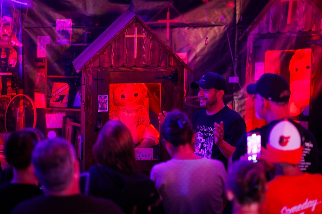 A man presents the Annabelle doll at a paranormal tour.