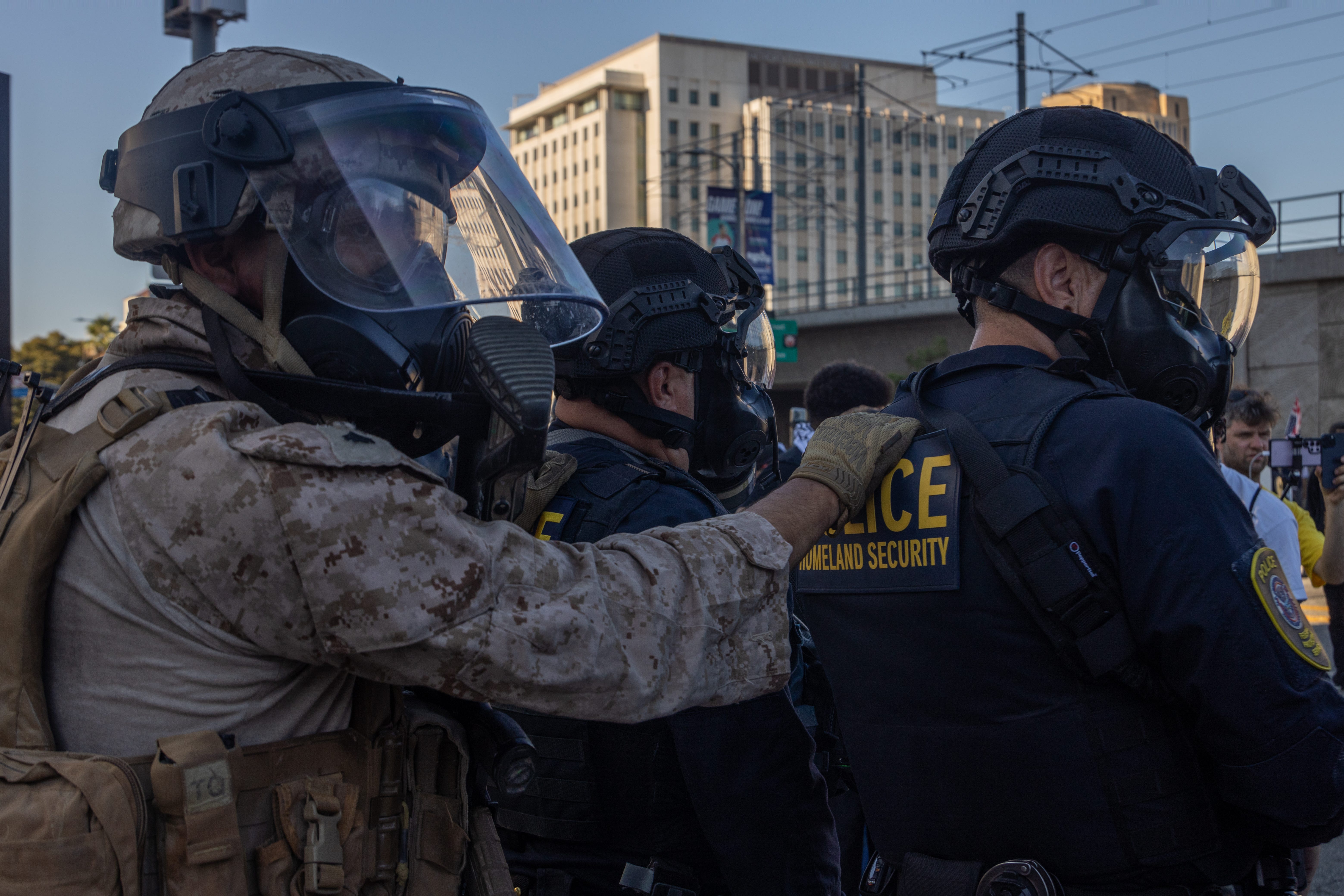 A Marine stands behind Homeland Security police in Los Angeles, July 4, 2025.