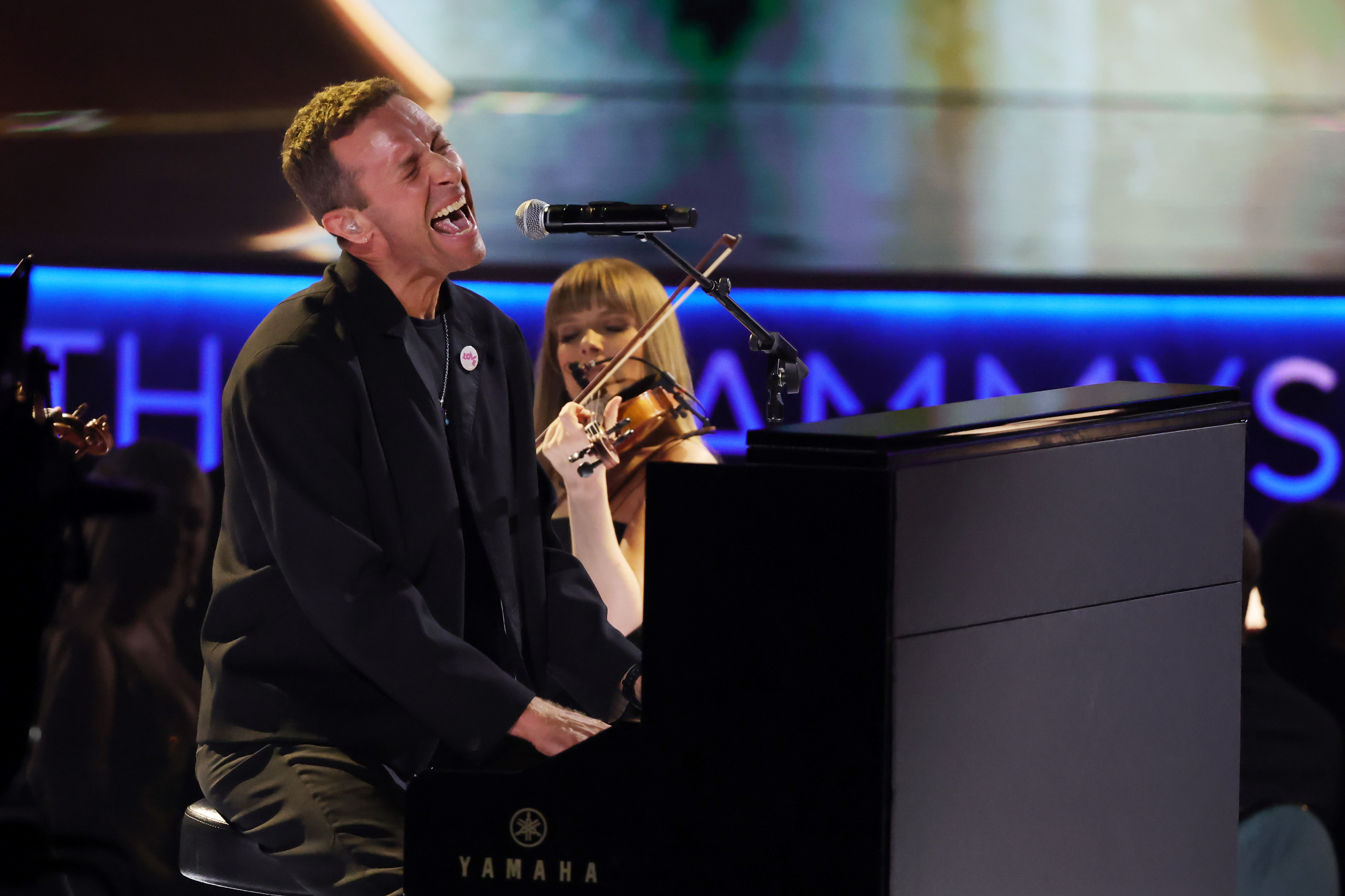 Chris Martin sings at a piano. 