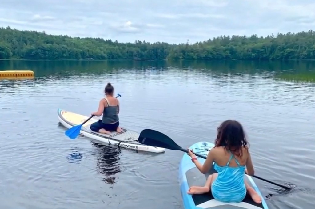 Two women paddleboarding on a lake.