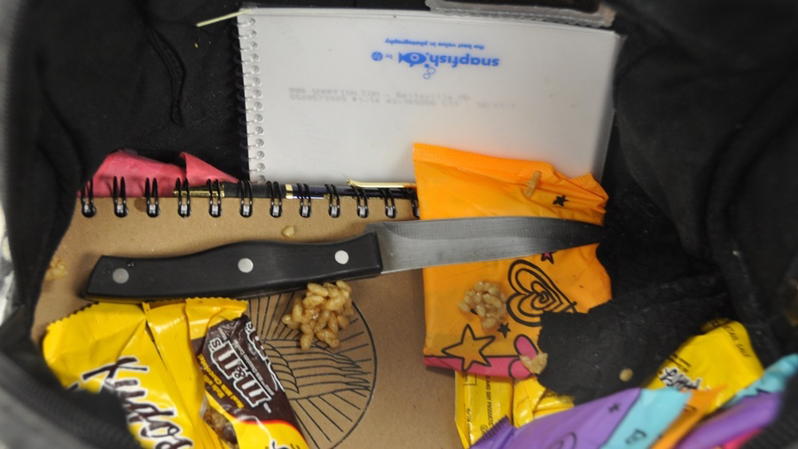 Evidence photo of a bag containing a knife, notebook, candy, and other items.