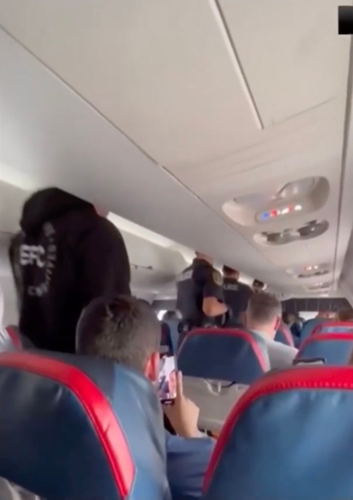 Police officers subduing a passenger on a Delta Airlines flight.