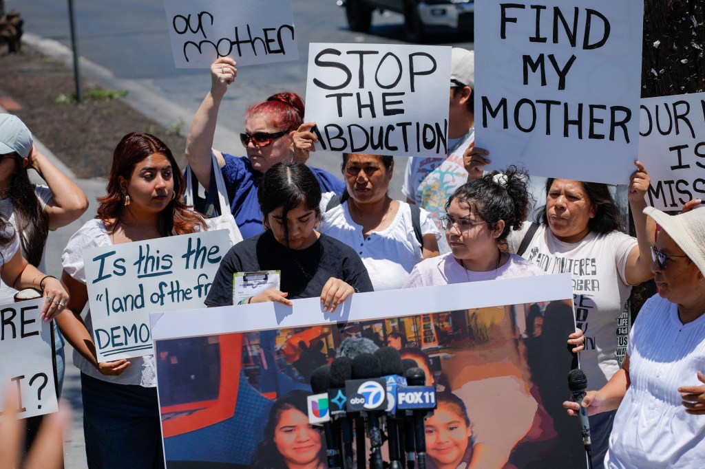 Protestors holding signs and a photo demanding information about a missing migrant mother.
