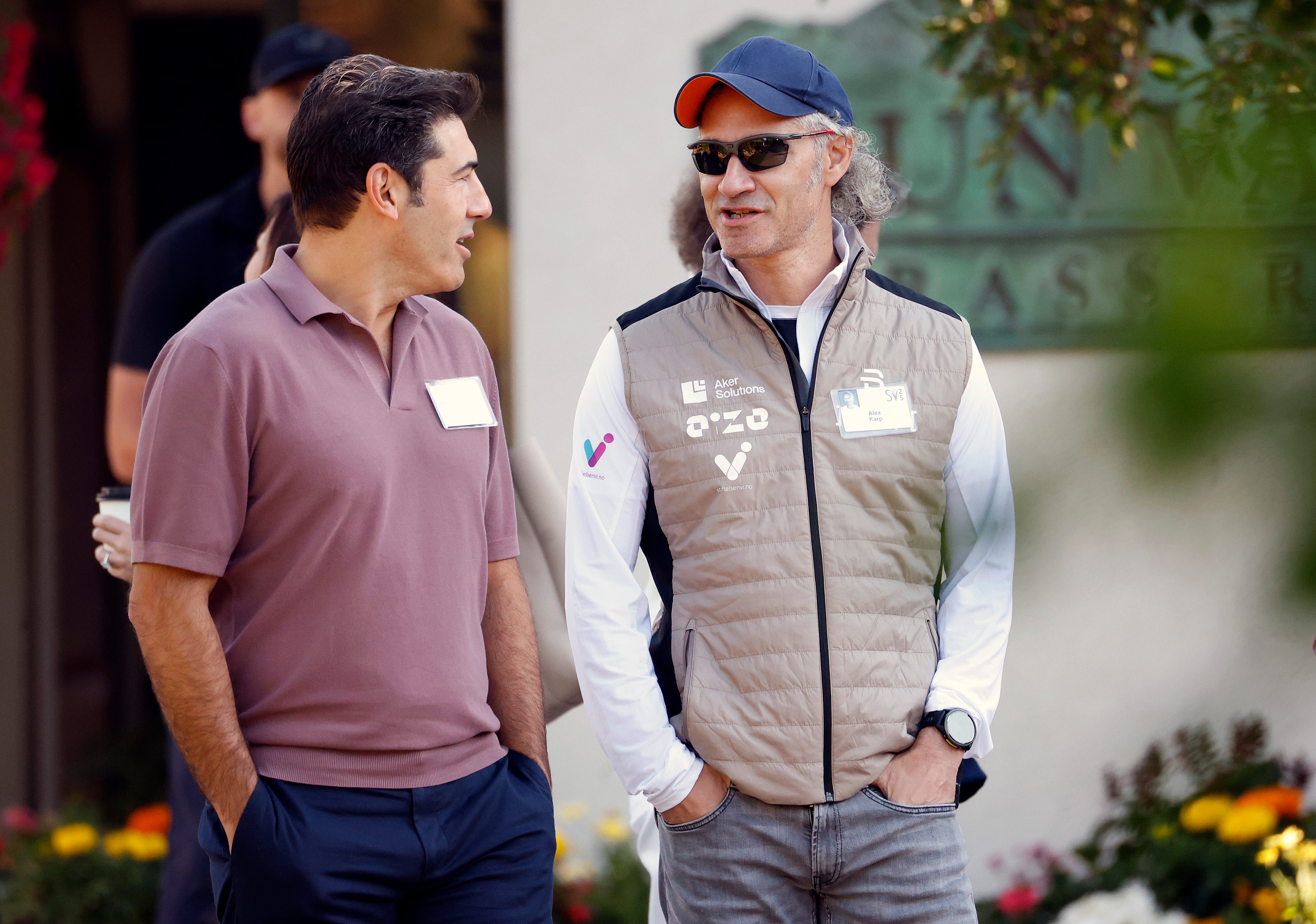 SUN VALLEY, IDAHO - JULY 10: Thomas Bernthal (L), founder and former CEO of Kelton Global, talks to Alex Karp, CEO of Palantir Technologies, as they walk together at the Allen & Company Sun Valley Conference on July 10, 2025 in Sun Valley, Idaho.