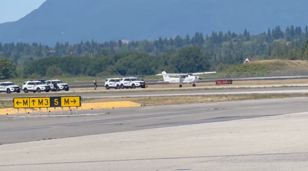 Police cars and a small plane on an airport tarmac.