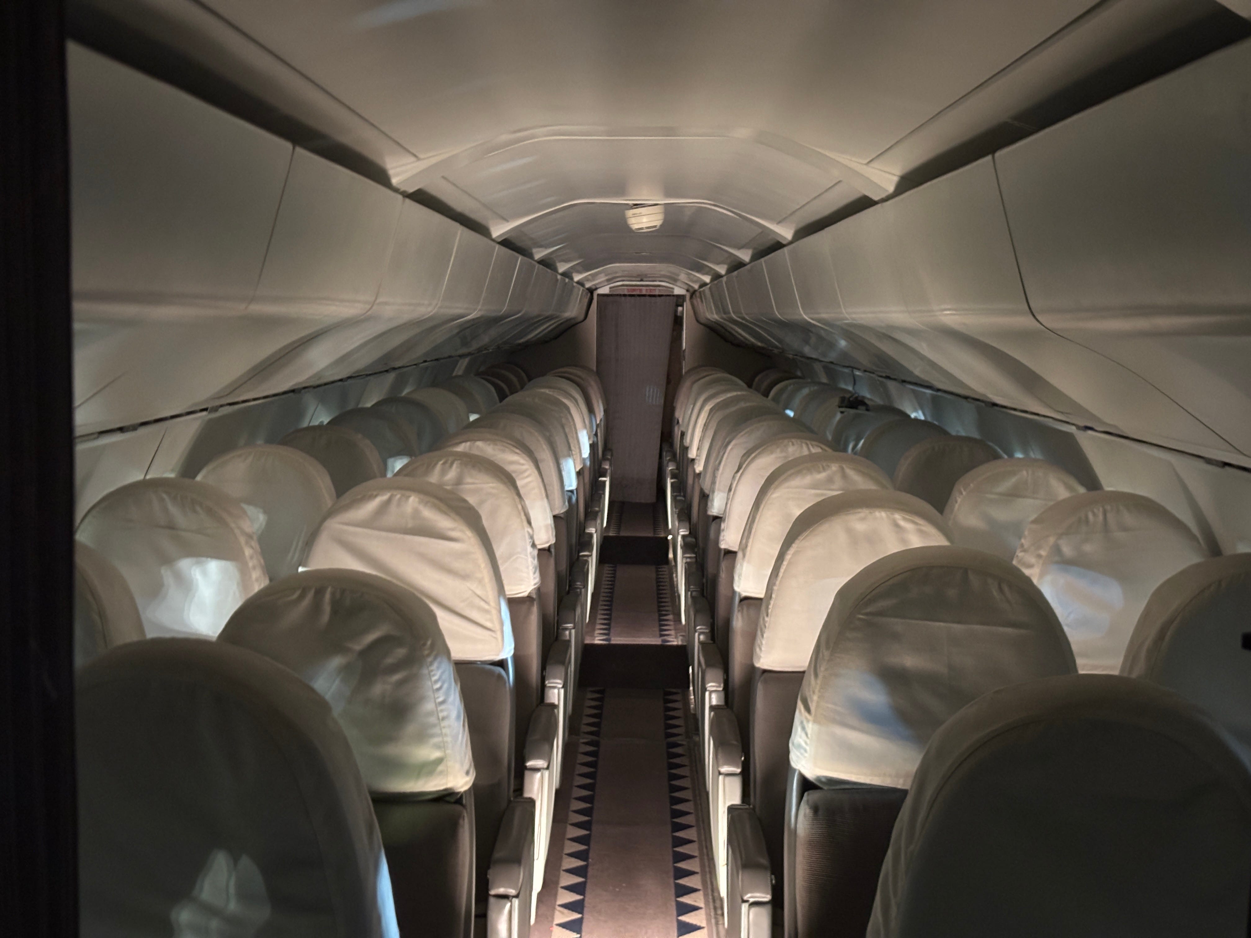 A view down the aisle of seats onboard Concorde Sierra Delta, with the headrests covered in plastic