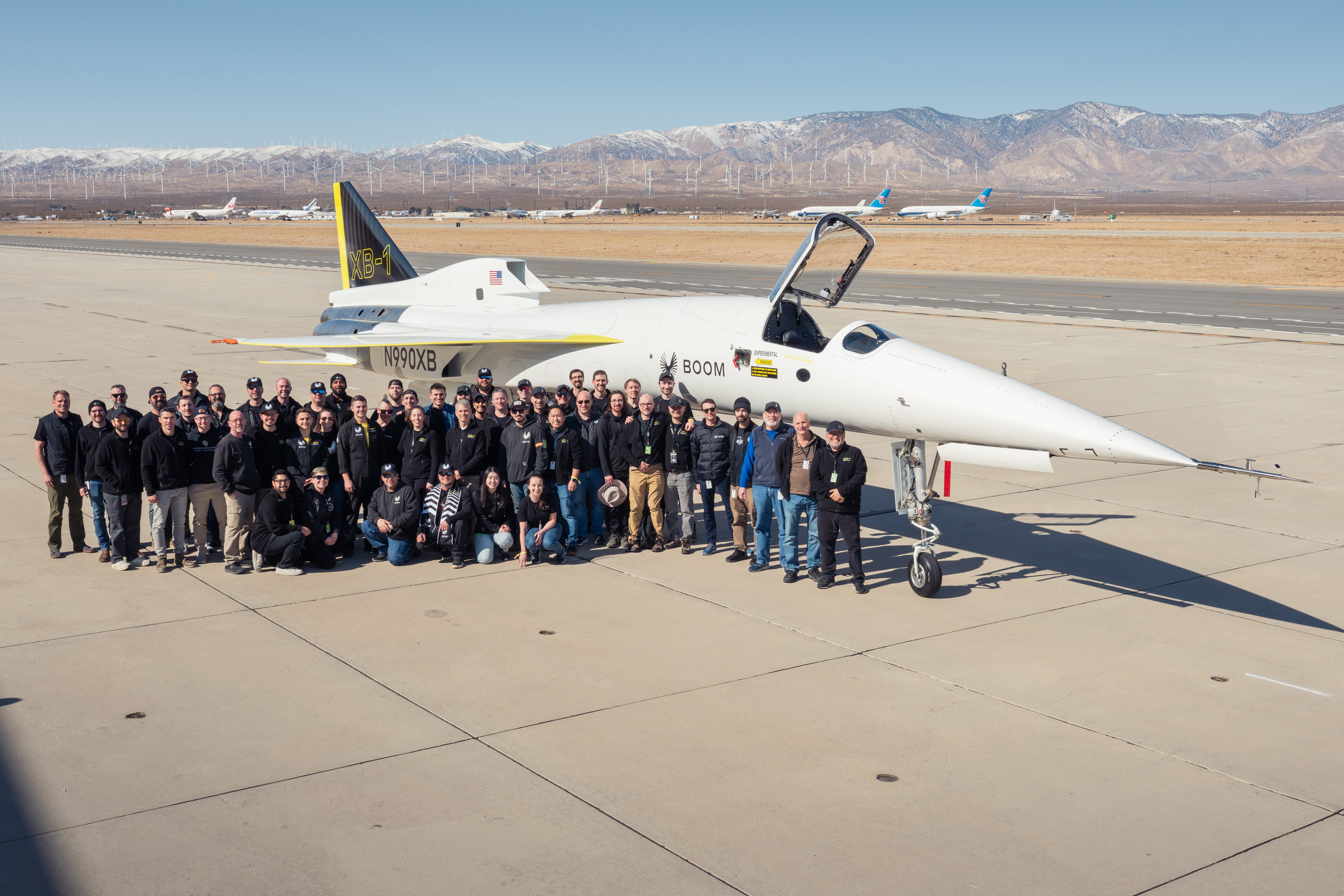 A group of people stand in front of "Baby Boom" the XB-1 prototype of the Overture supersonic airliner