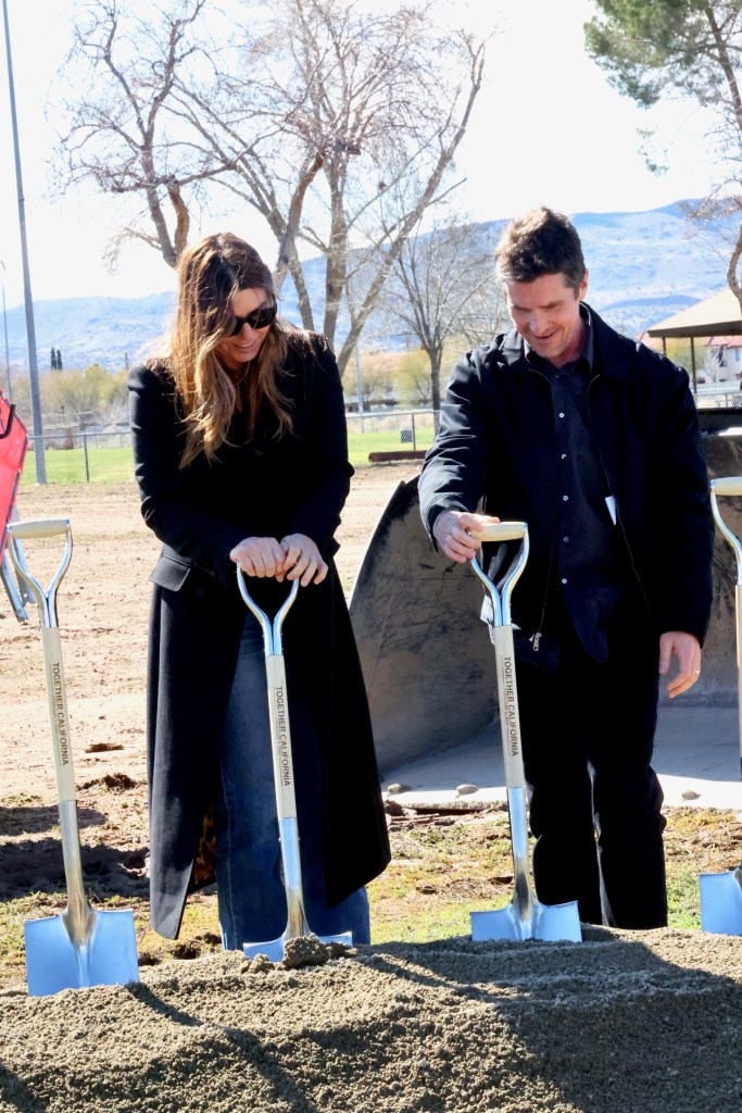Christian Bale and another person participate in a groundbreaking ceremony.