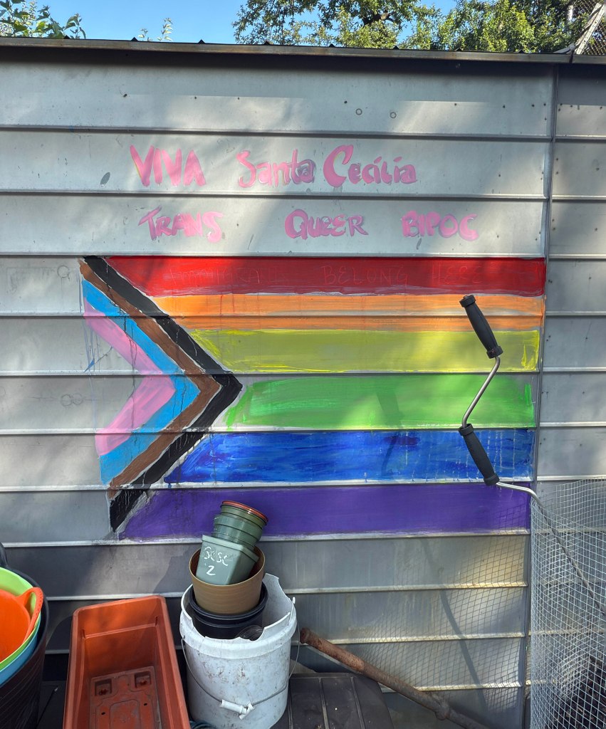 Graffiti of a progress pride flag on a metal wall.
