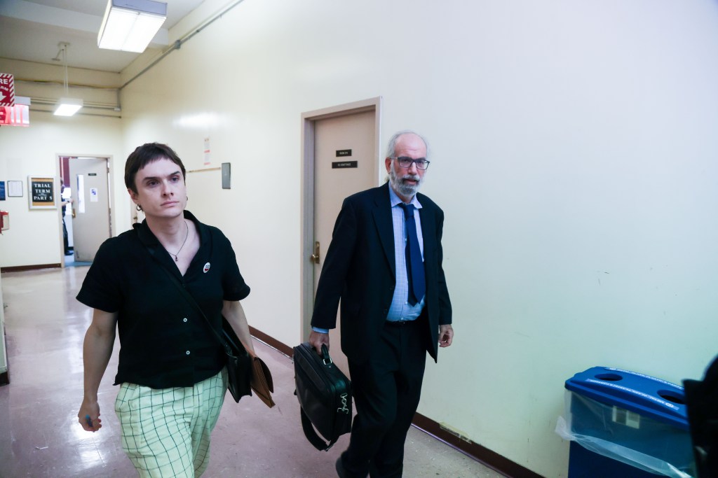A lawyer and client walk down a courthouse hallway.