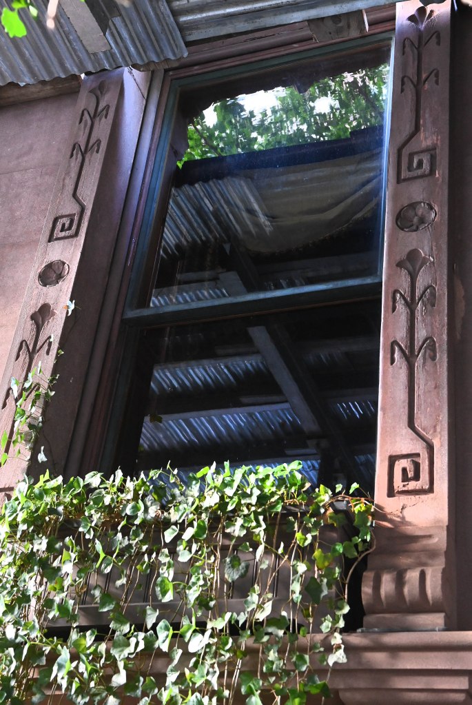 a close up of one of the windows of the historic townhouse with unique carvings along the side of the window