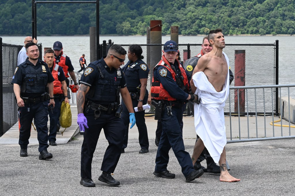 Police officers arresting a shirtless man wrapped in a white sheet.