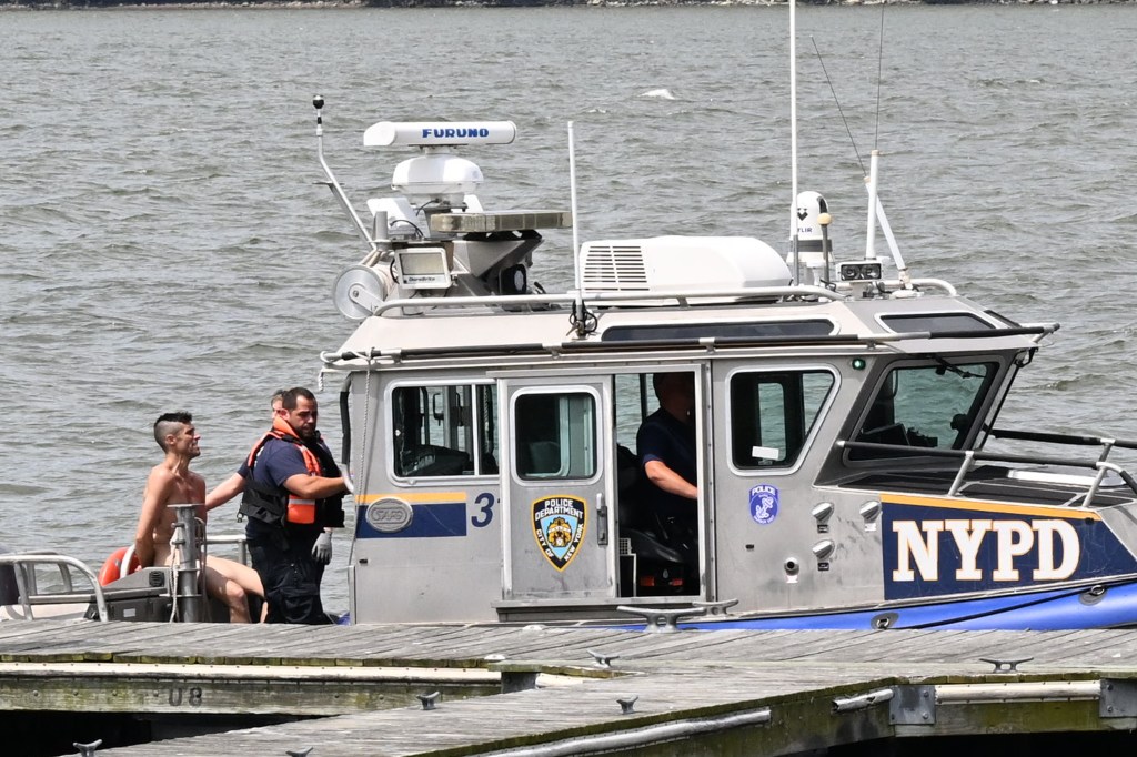 A naked man being taken into custody by NYPD officers on a boat.