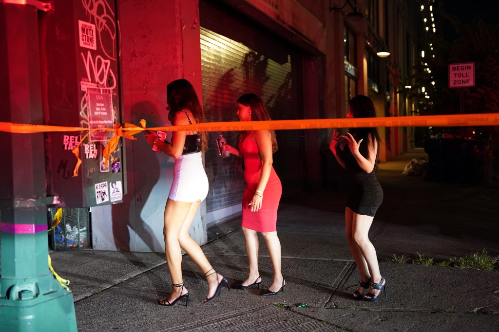Three women near crime scene tape at night.