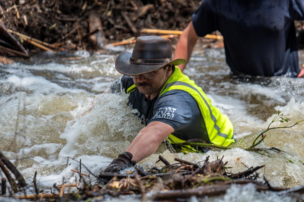 Man clearing debris from a flooded river in Texas.