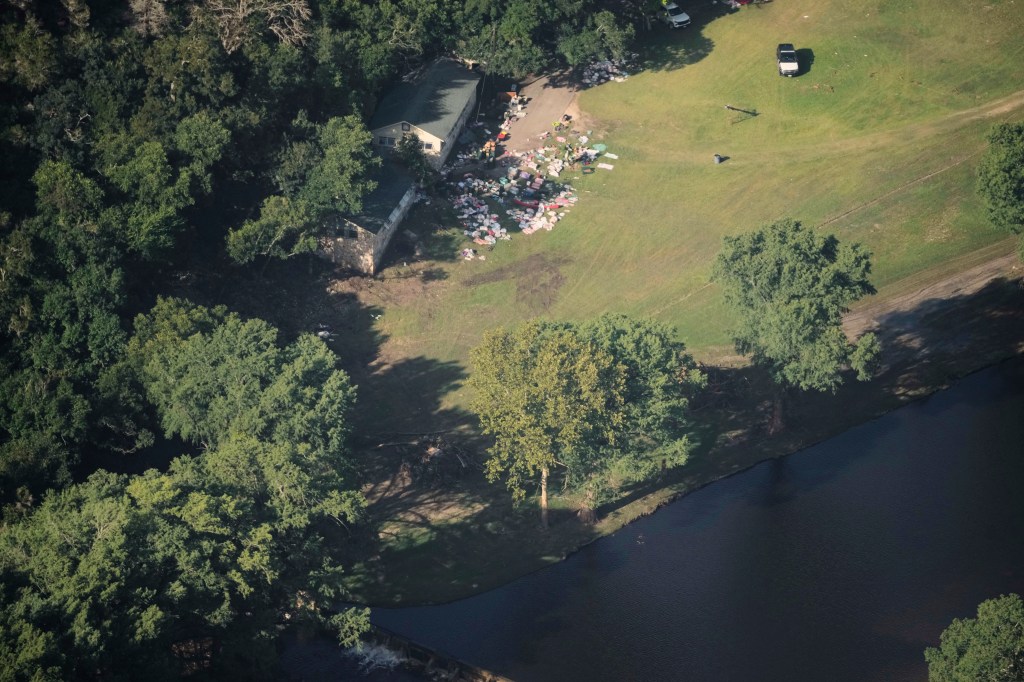 Aerial view of flood damage in Texas, showing a house surrounded by debris.