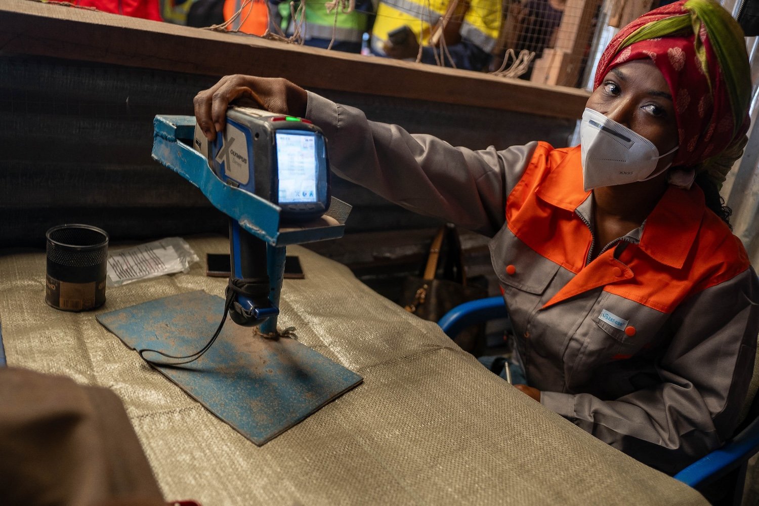 A woman in a mask touches an XRF gun.