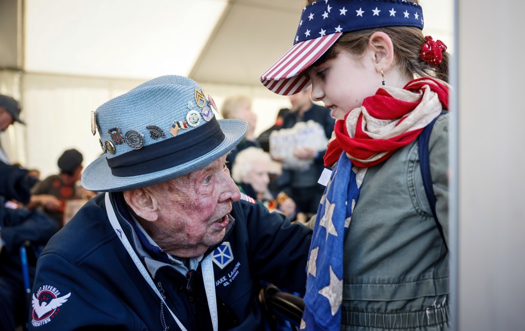 Veteran SSgt. Jake M. Larson speaks with a young girl.