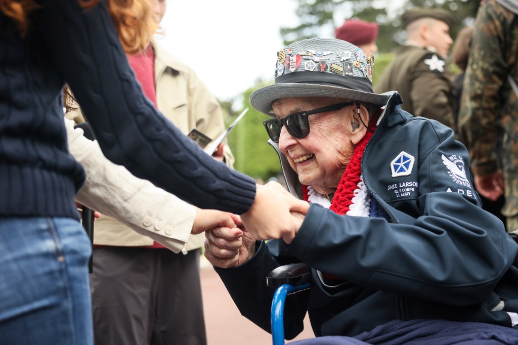 World War II veteran Jake Larson holding hands with young people.