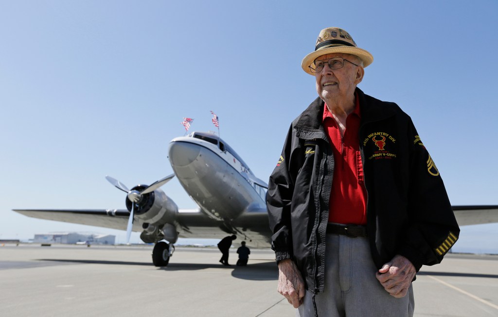 D-Day veteran Jake Larson standing in front of a World War II-era airplane.