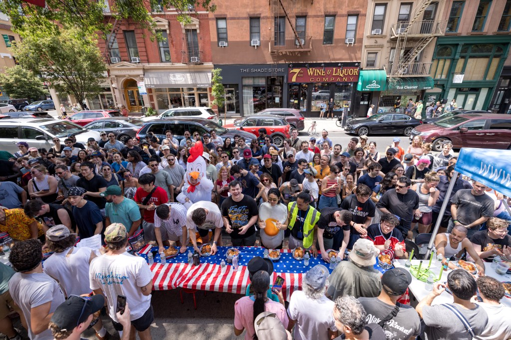 A large group of people watching a chicken wing eating contest.