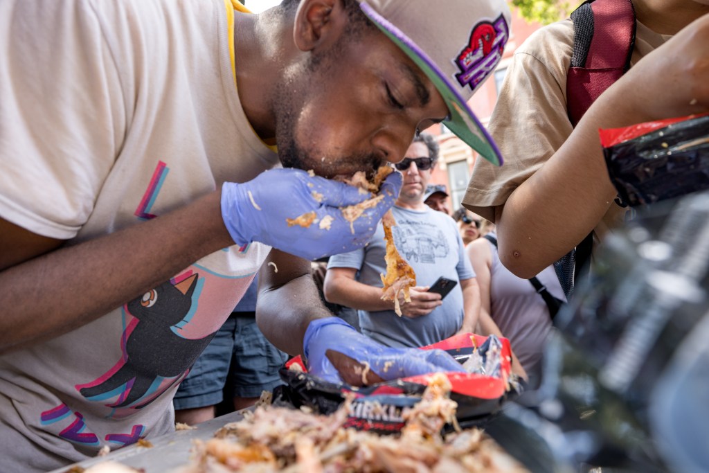 A man wearing gloves eats pulled pork in a competitive eating contest.