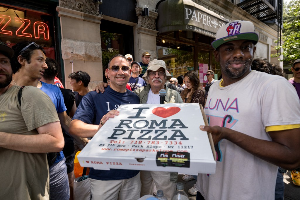 People holding a Roma Pizza box.