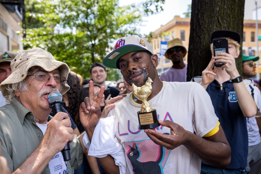 Man holding a chicken-shaped trophy and giving the peace sign.