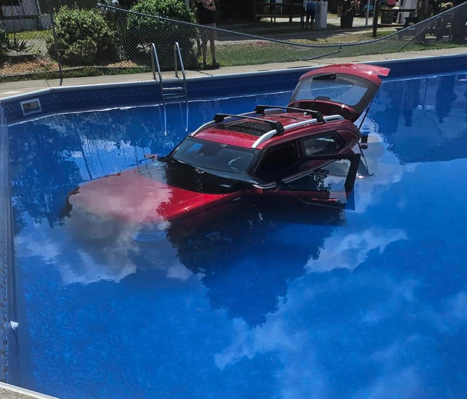 Red SUV submerged in a swimming pool.